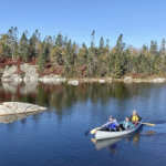 在一个美丽晴朗的秋日里，三个人坐在湖上的圆锥体里。