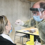 检测诊所的一名男护士正在从一名女性患者身上提取covid检测棉签。