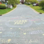 在一条死胡同的人行道上，用彩色粉笔画了一个大圆，中间写着“谢谢”，边上用其他语言写着“谢谢”，里面写着各种职业，比如杂货店工人、科学家、艺术家、护士、邮递员等。