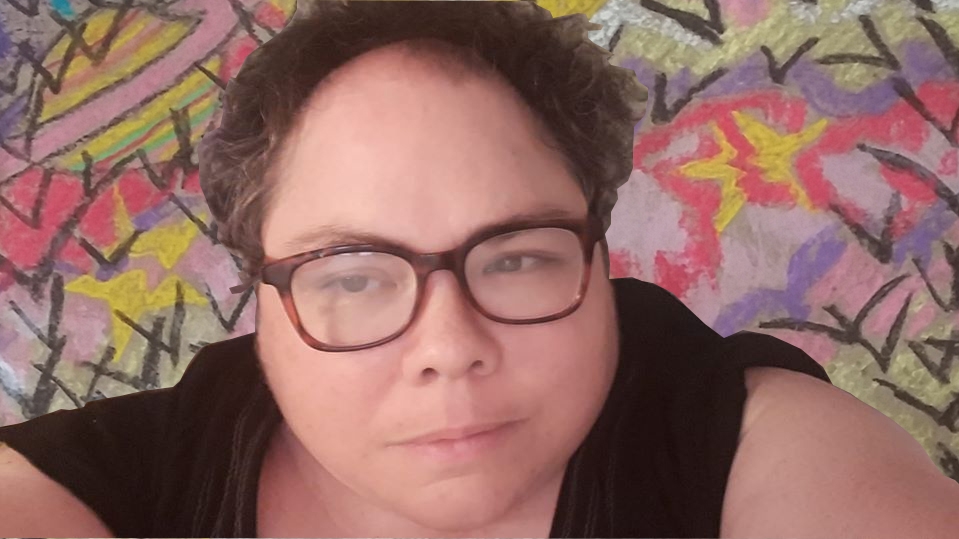 卷发、戴眼镜、身穿黑色上衣的女性自拍。一幅色彩鲜艳的画在背景中隐约可见