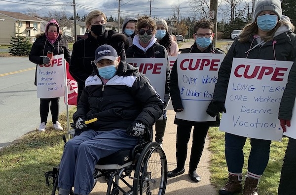 一名坐在轮椅上的男子被举着标语的工会成员包围