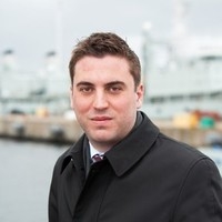 安德鲁·高夫的头部照片，深色衣领，背景模糊。