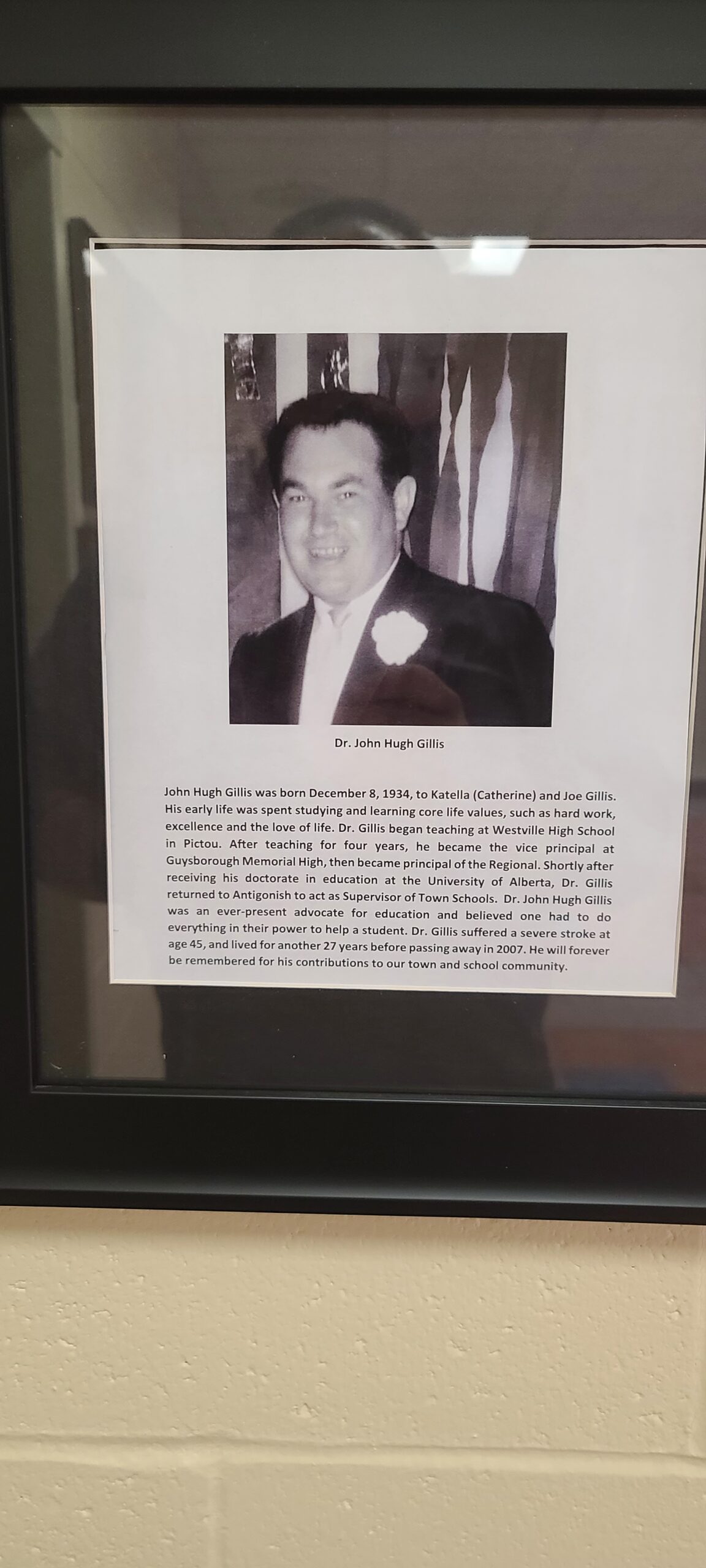 一张牌匾的照片，上面有一个穿着西装的微笑男人的照片和下面的文字。