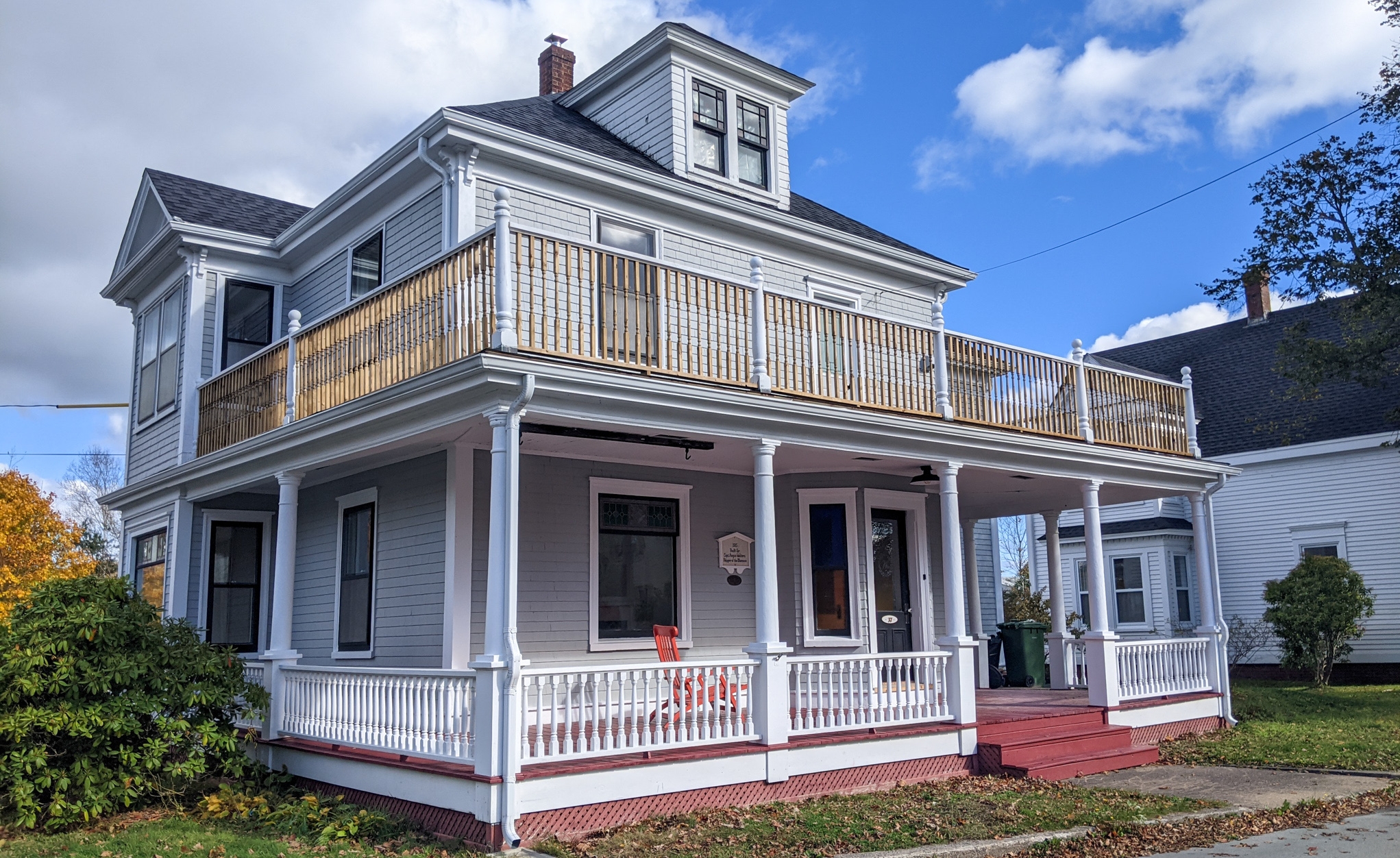 卢嫩堡一处历史建筑的照片。该住宅是一栋两层的白色住宅，在主楼和二楼都有环绕式门廊。阁楼上有一扇窗户从屋顶伸出来。