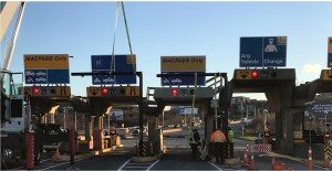 周日，在麦凯大桥的收费站，一个新的碰撞条预警系统正在安装到位。通行费包括几个车道，上面有蓝色和黄色的标志，表明车辆可以进入。早期预警系统是一个栅栏，让大型卡车知道它们可能无法进入屋顶较短的车道。