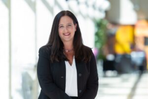 克里斯汀·钱伯斯站在一个灯火通明的房间里，对着镜头微笑。