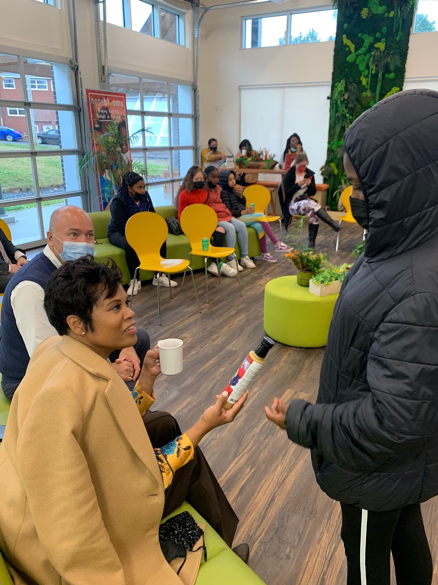 安大略黑人女议员Marci Ien拿着一瓶沙拉酱在希望之花与一名黑人青年交谈。