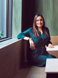 哈塞尔·阿维莱斯坐在餐厅摊位前的照片。她穿着一件蓝色的连衣裙，留着黑色的长发。