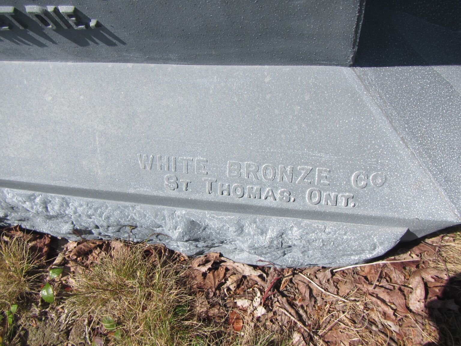 墓碑的细节，上面写着“安大略省圣托马斯白青铜公司”