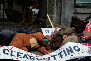 Protestors, including one in a moose costume, lay down on Hollis Street and are draped in a sign that says stop clearcutting