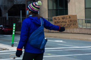 在哈利法克斯，一名抗议者在省议会大厦外举着标语阻止交通。上面写着