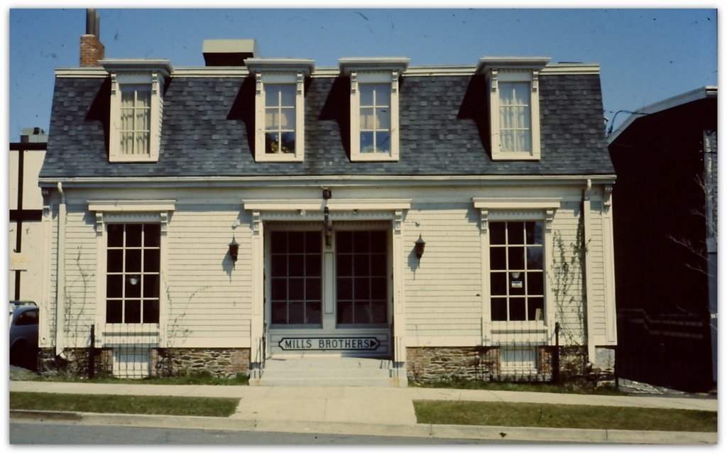 古老的木制两层建筑，有四扇天窗，双开门两侧各有两扇窄窗。门下有一个牌子，上面写着米尔斯兄弟。