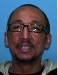 特伦斯·帕特里克·伊扎德的照片，他是一个发际线向后退去的黑人。在这张照片中，他戴着眼镜，穿着灰黑相间的连帽衫。