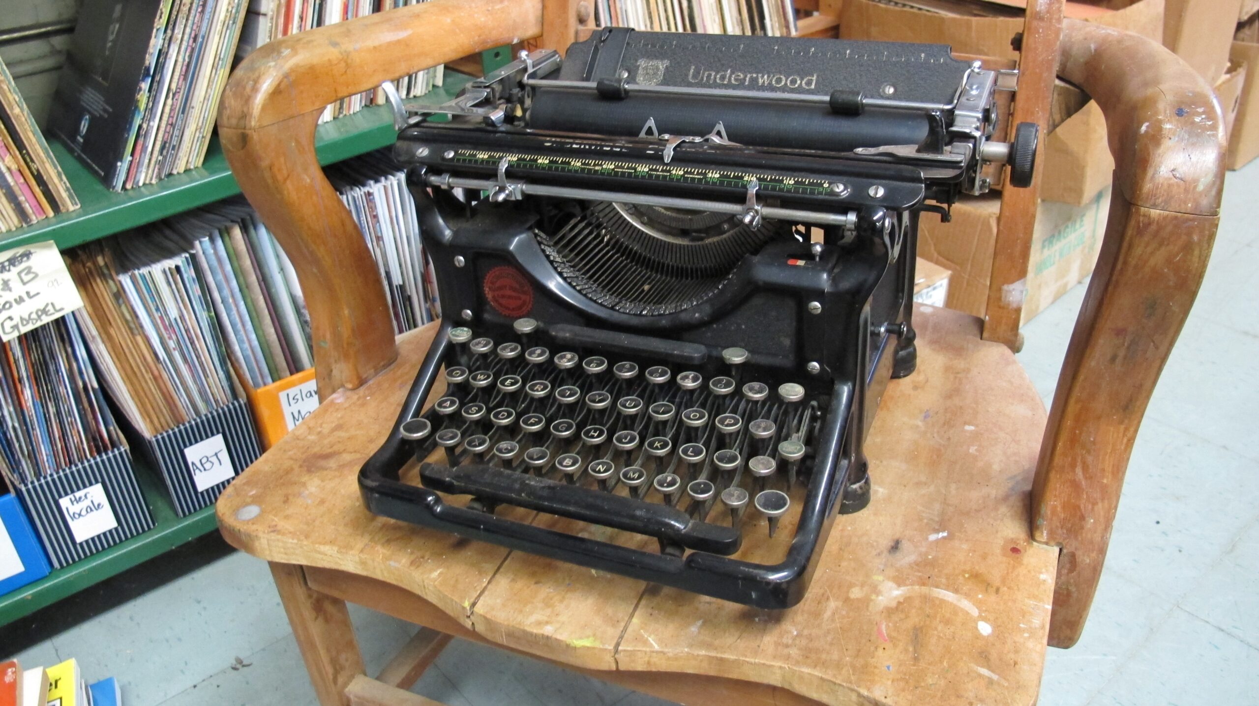 一台老式安德伍德手动打字机放在木椅上，背景是书架。