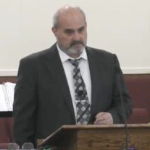 牧师罗伯特·史密斯站在他的讲坛上，脸上带着严肃的表情