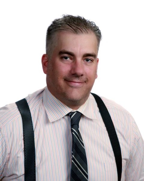 德文·麦克斯韦尔身穿浅色衬衫、黑色领带和黑色背带裤的中景