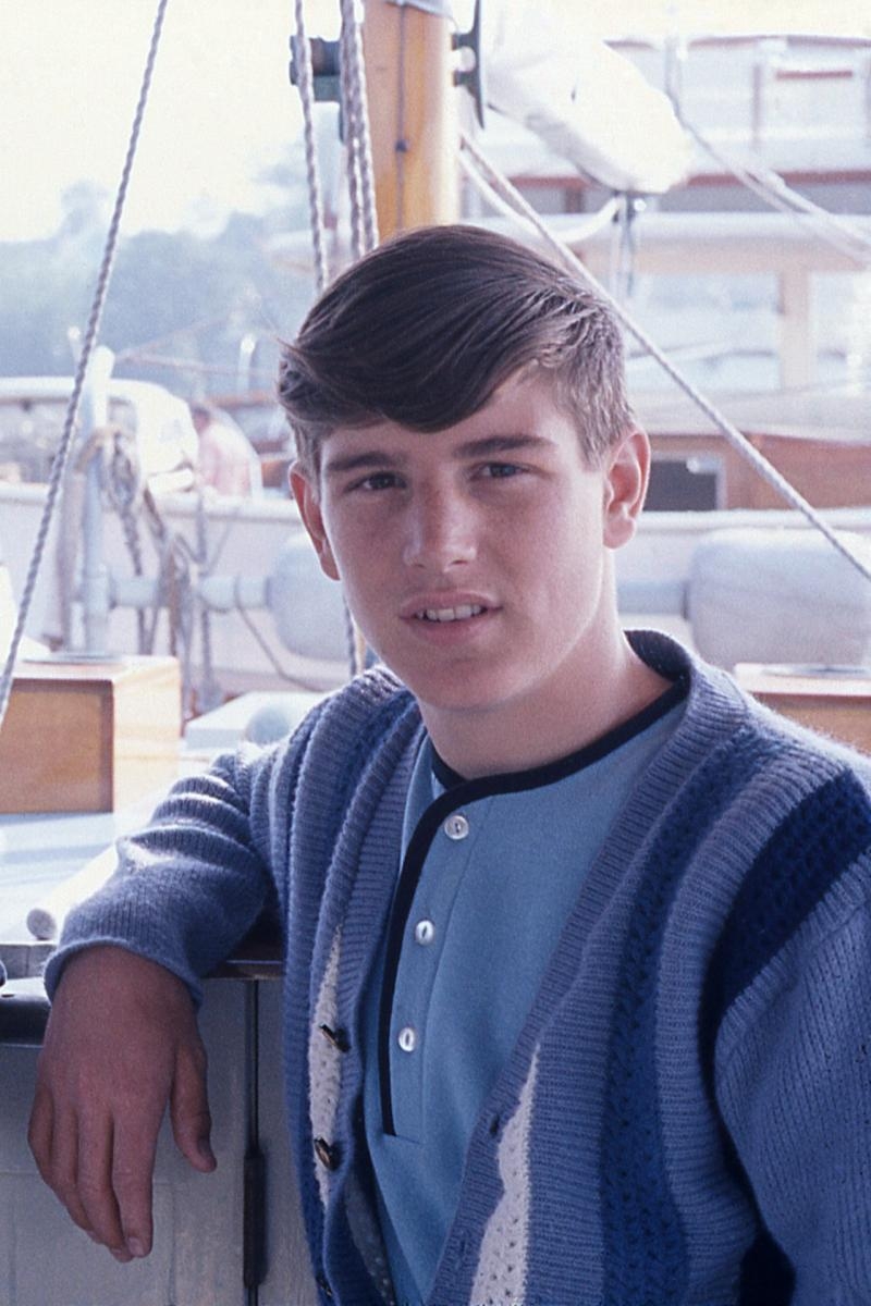 一个严肃的白人少年看着镜头。看来他可能在一艘帆船上。