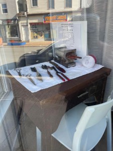 这是黑人美文化展上展出的旧发型熨斗照片。熨斗放在商店橱窗里的一张深棕色的桌子上。