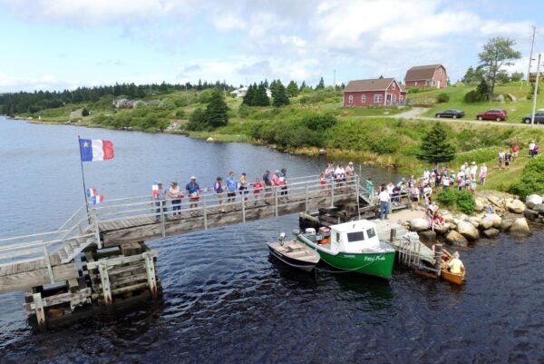 阿卡迪亚国旗悬挂在一座木桥上，河岸附近的草地上，观众聚集在那里观看托尔湾地区的鸭子比赛。