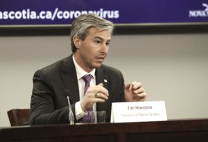 一个坐在办公桌前的男人。这个人就是蒂姆·休斯顿总理。