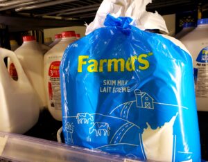 在杂货店的展示柜里，摆放着一袋装着三个“枕头袋”的牛奶，前面摆着四升的混合牛奶罐。