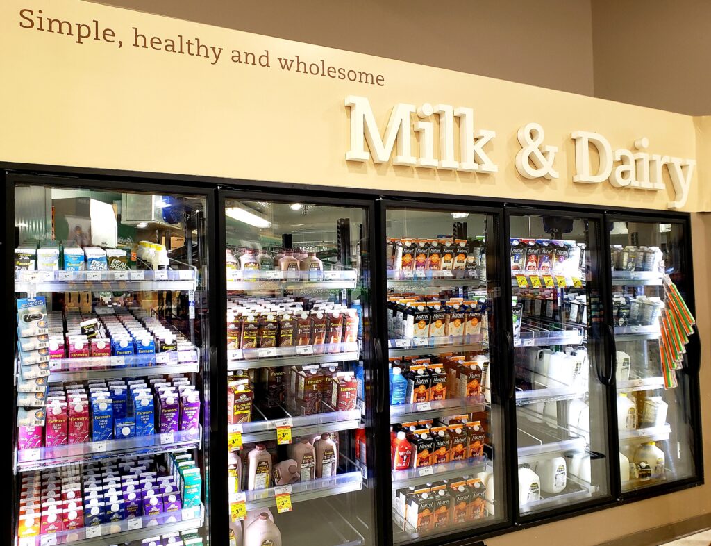 杂货店的牛奶和乳制品柜，里面摆满了各种牛奶和奶油制品。冰箱顶部的标志写着简单、健康、健康