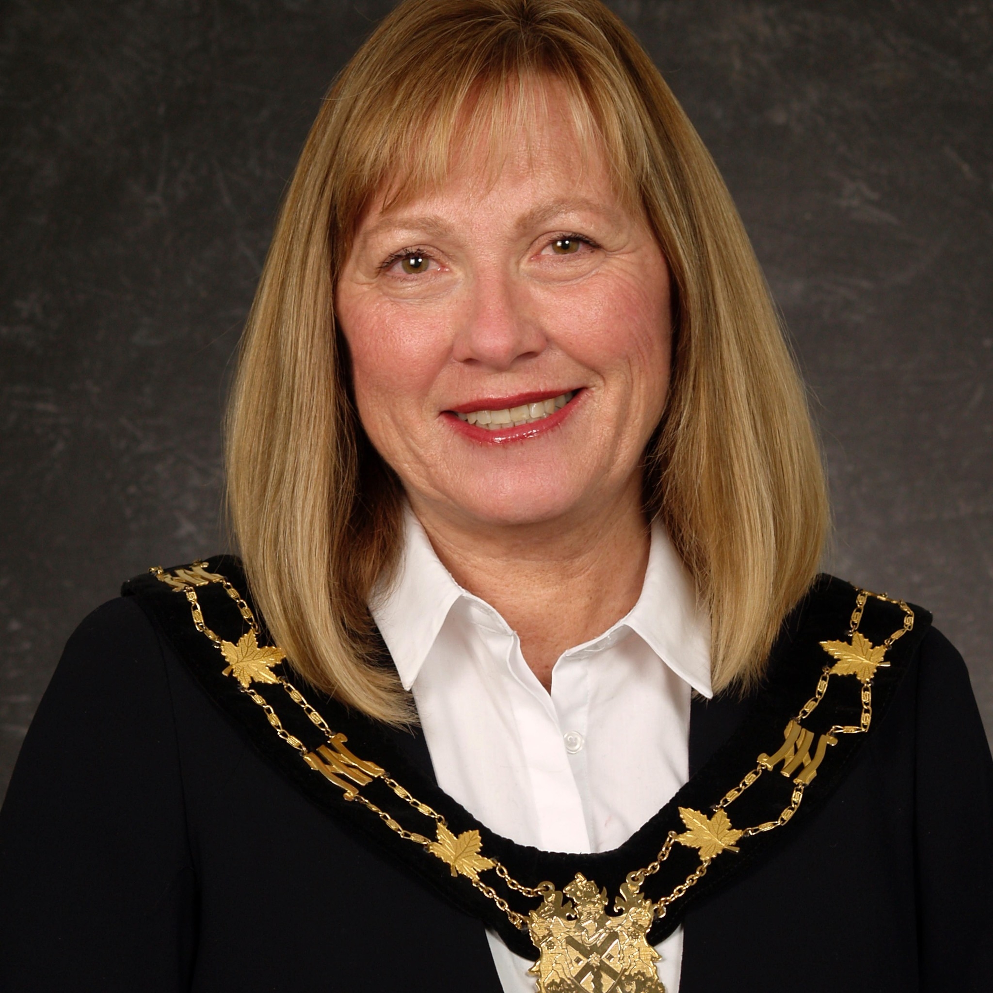 南希·迪克斯的头像，一个白种女人，一头金色长发，穿着一套带有金叶细节的市长制服。