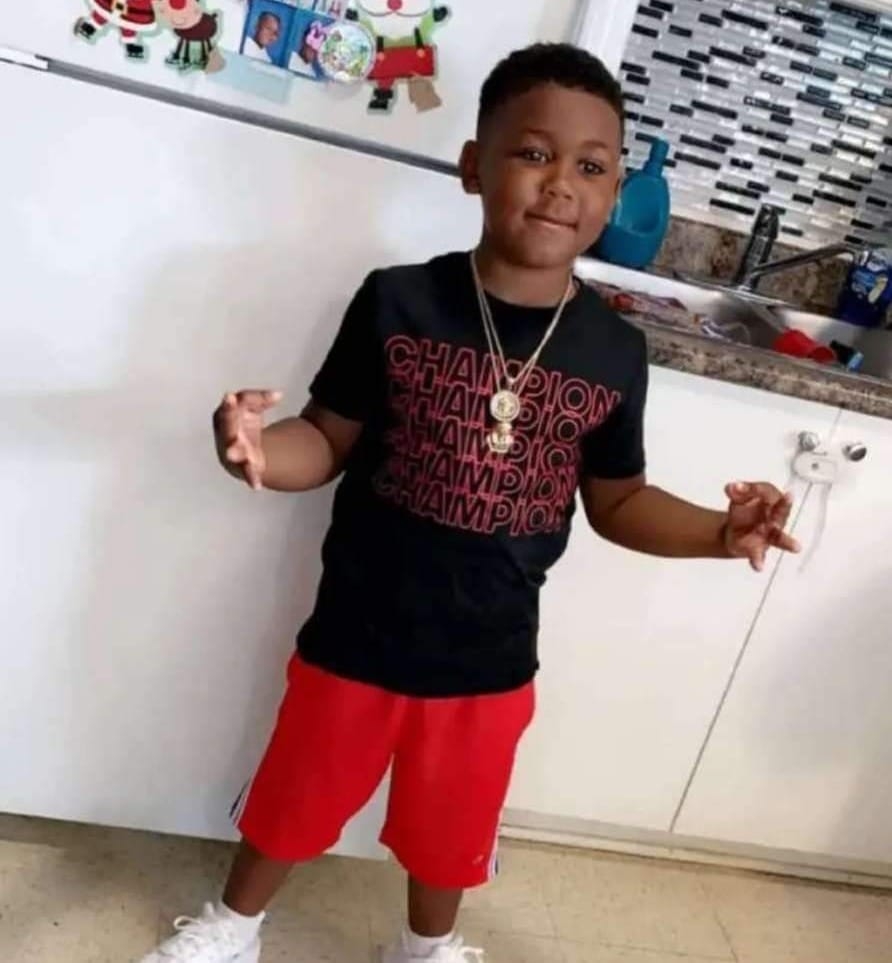 穿着黑色t恤和红色短裤的黑人小男孩在厨房里摆姿势