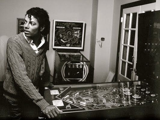 迈克尔·杰克逊在弹珠机旁。他的手放在脚蹼上，看着我的身后。