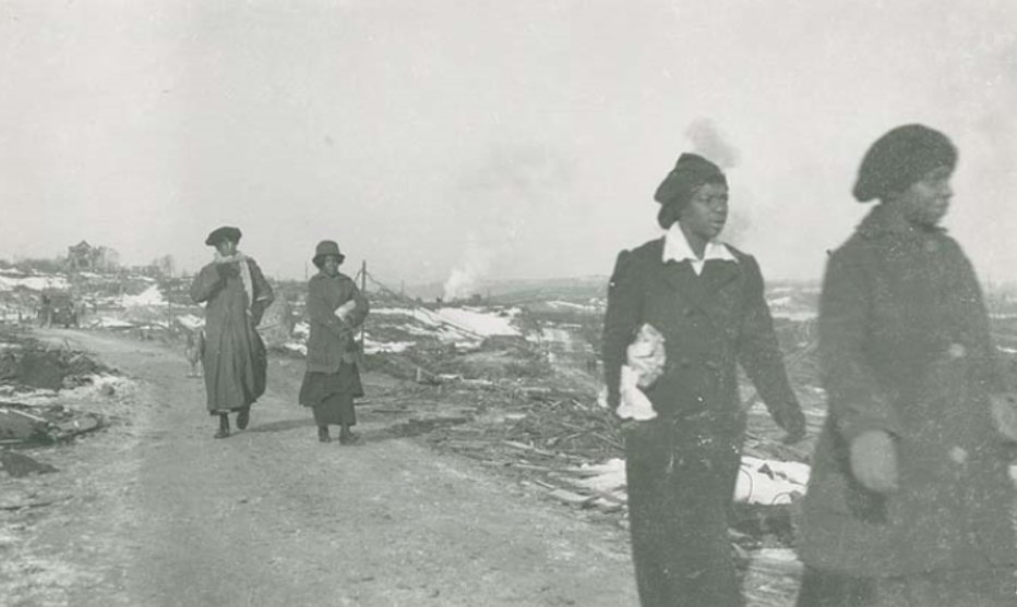 A black and white photo of women from Africville walking through the community after the Halifax Explosion.