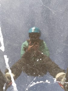 一名滑冰者，穿着厚重的雪具，戴着面具、头盔和护目镜，在谢湖的冰冻冰中拍摄自己的倒影