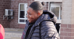 本周，凯拉·波登(Kayla Borden)在法院大楼外接受上诉。波登是一位年轻的黑人女性。这是她微笑着穿着一件蓬松的黑色夹克。