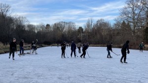 在一块巨大的天然冰面上，两场比赛正在进行，冰的两端各有一场。天渐渐黑了，雪开始堆积在冰上。大约有24个十几岁的男孩在玩。