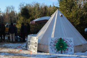 A tent in the snow. Propped against it, signs saying 