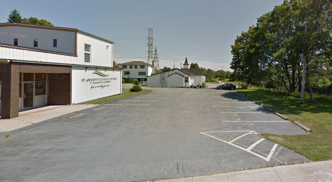 停车场，左边有一座教堂，圣安东尼天主教堂的字样清晰可见。背景中是一座较小的建筑，有着低矮的尖顶。