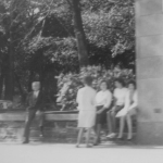 人们坐在建筑物旁人行道上的矮墙上的黑白照片