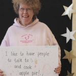 白人妇女Beth MacLean举着一个牌子，上面写着“我喜欢有人聊天和做苹果派!”