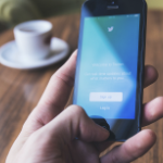 一个拿着手机的男人的手打开了Twitter的注册页面