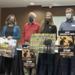 抗议者在一次会议上戴着口罩并举着迹象