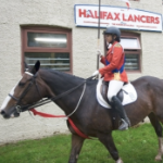 一个正式涂装的年轻女孩骑着旗帜骑着一匹黑马