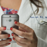 她的手机上穿着医生的白色外套和听诊器类型的白人妇女