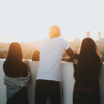 两个年轻的妇女和阿扬格男子在阳台上望着日落