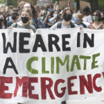 People at a protest hold a large banner which reads 