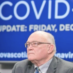 Dr. Robert Strang looking rather tired in front of a huge screen with 