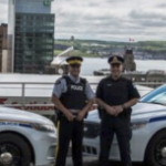 An HRP officer and an RCMP officer flanked by their patrol cars on Citadel Hill