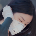 一个亚洲女人调整她的白色面具