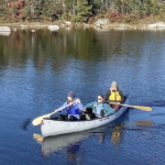 三个人在秋天的湖面上划着独木舟