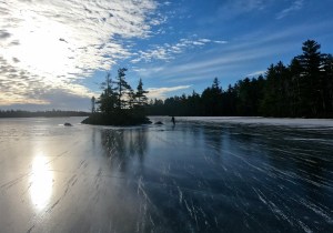 远处的滑冰者绕着冰封的大拉哈湖上的一座小岛旋转。这是一个相当晴朗的日子