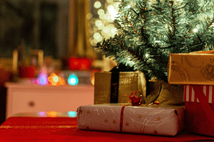 红色桌布上放着一堆包装精美的金盒子，背景是一棵绿树，背景是闪烁的灯光。