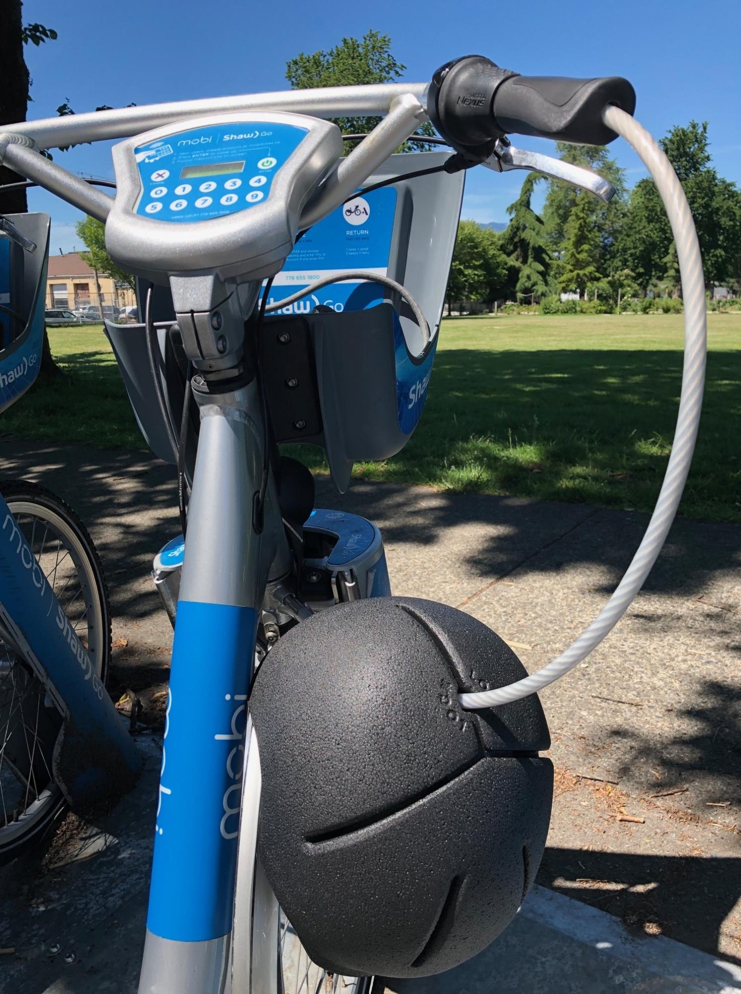 用缆绳固定在自行车上的黑色泡沫头盔。